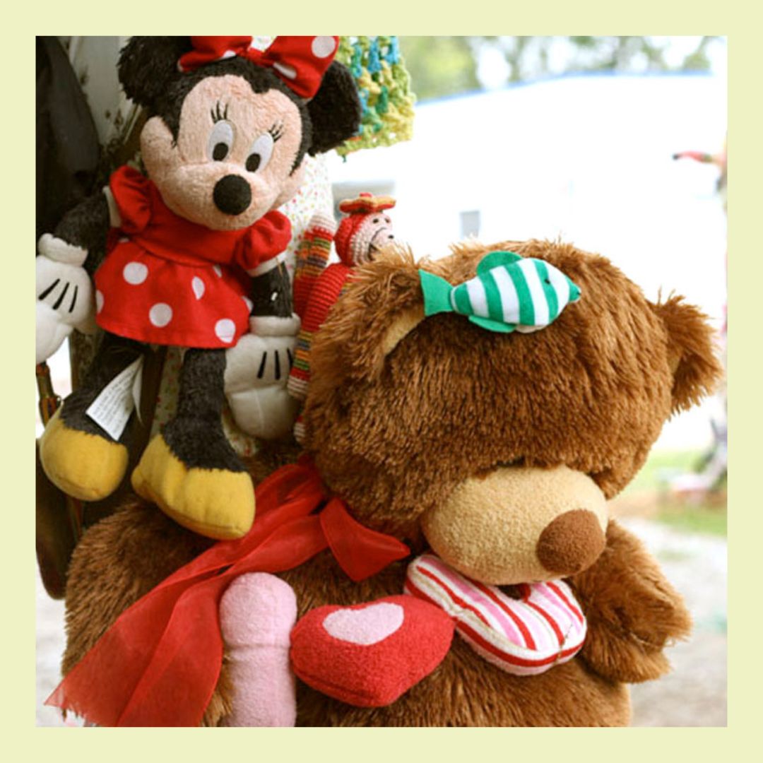 Stuffed animals. on left mini mouse in a red dress. on right large brown teddy bear with green fish on head